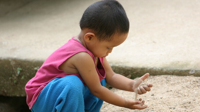 Niño jugando con un puñado de tierra